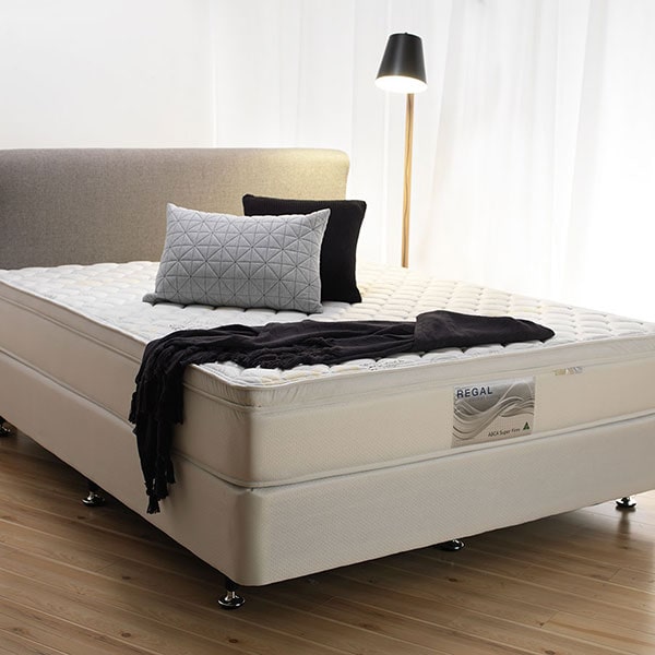  A modern, well-made bed with a plush mattress, neatly arranged pillows, and a black throw blanket in a minimalist bedroom setting.