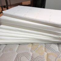 A stack of white layered pillows on a mattress, showcasing their adjustable thickness.
