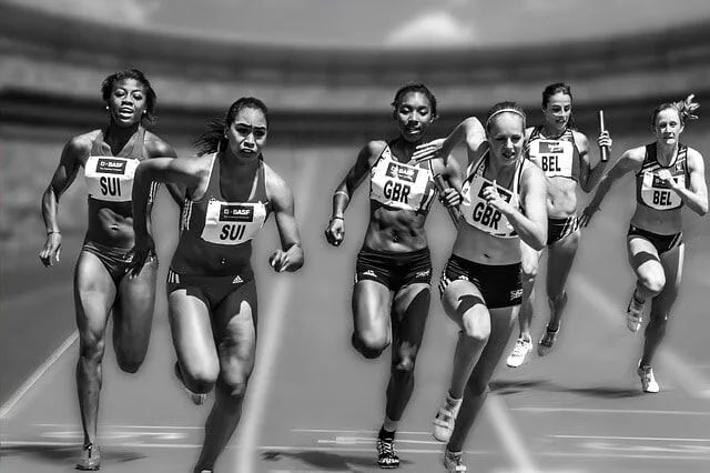 Athletes sprint in a relay race, highlighting the physical demands that can lead to knee and ankle injuries, emphasizing the need for chiropractic care at Upright Body Renewal.